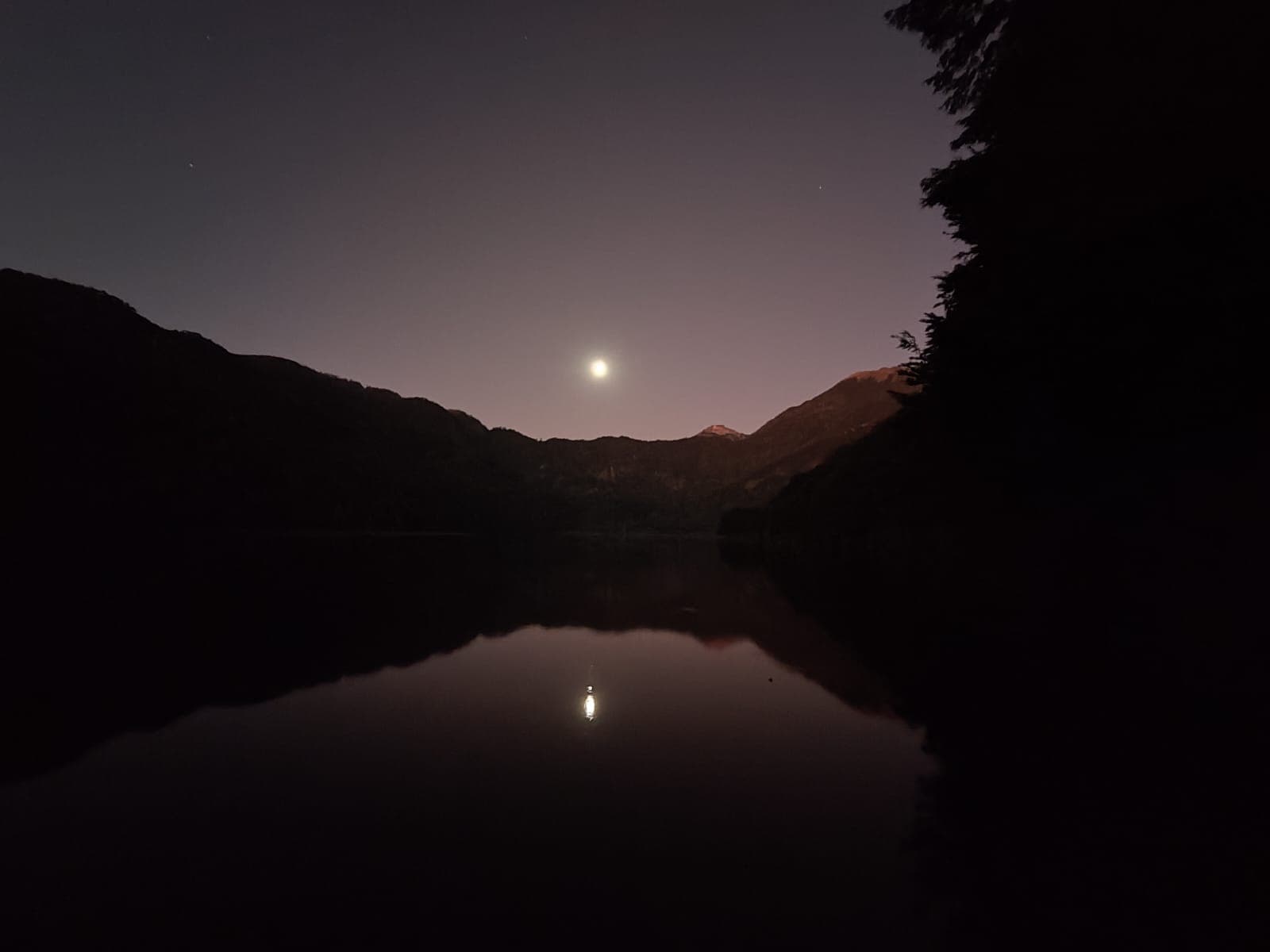 Luna llena reflejada en el Lago Tinquilco de noche con siluetas de montañas