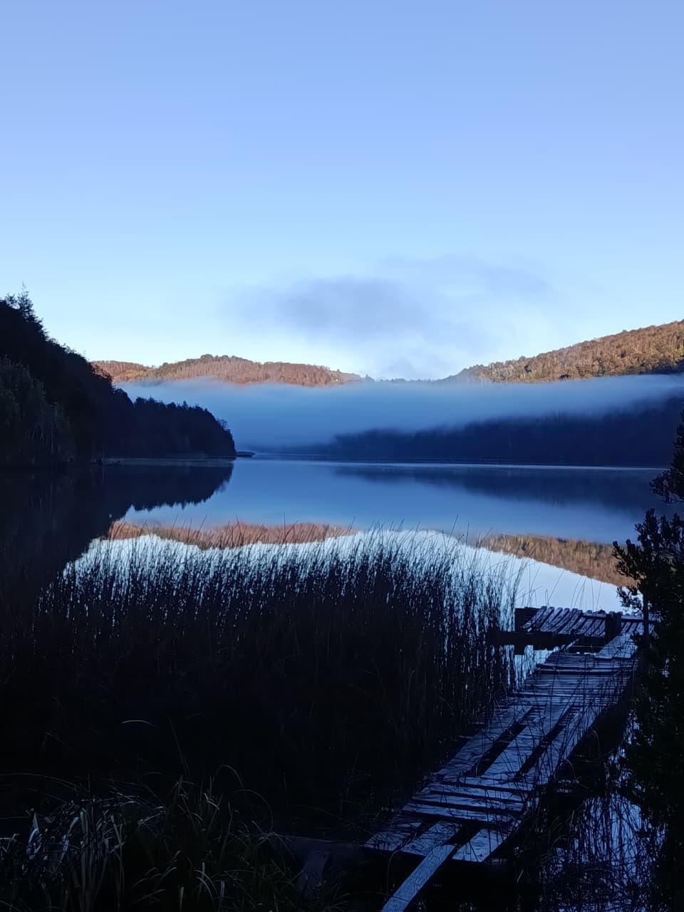 Canoa roja con dos personas en el lago al atardecer bajo la luna