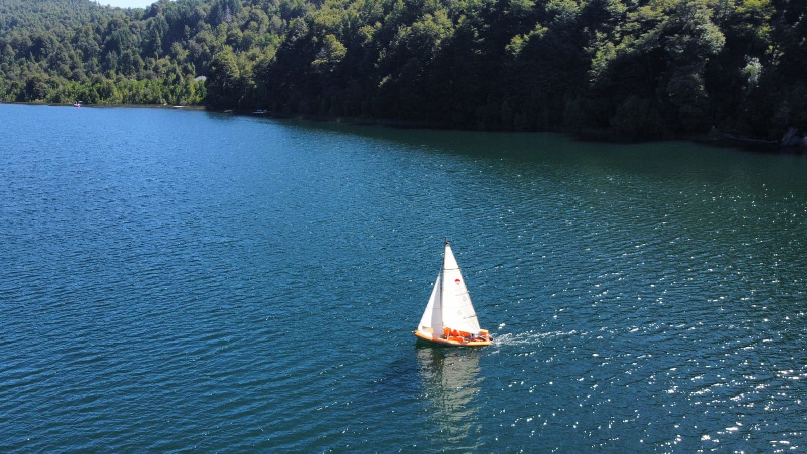 Velero en el Lago Tinquilco visto desde el aire con bosque nativo en las orillas